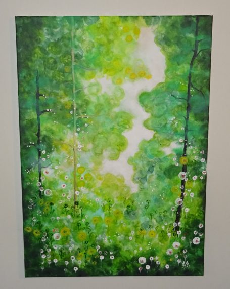 Gröna skogar med ljusa inslag och blommor i förgrunden.